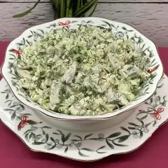 Pyszna sałatka ze śledzi marynowanych z jajkiem, udekorowana świeżym koperkiem, podana w ozdobnej misie.