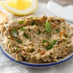 Pyszna pasta rybna na kanapki, doprawiona ziołami i papryką, podana z pieczywem i cytryną.