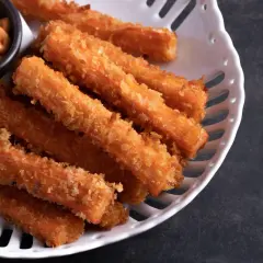 Chrupiące paluszki surimi w panierce, idealne do ciepłych dań. Podane z kremowym sosem.