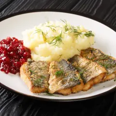 Pyszna ryba na obiad, podana z puree ziemniaczanym i żurawiną.