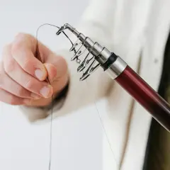 Dłoń przygotowuje wędkę, sprawdzając długość przyponu na leszcza z gruntu.