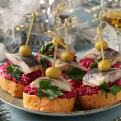 Wykwintne potrawy ze śledzi matiasów na chlebie z buraczkami, oliwką i pietruszką, udekorowane na święta.