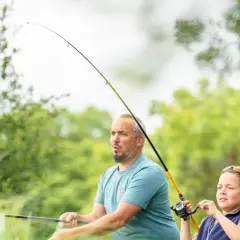 Ojciec i syn w akcji wędki, cieszący się wspólnym wędkowaniem wśród zieleni.