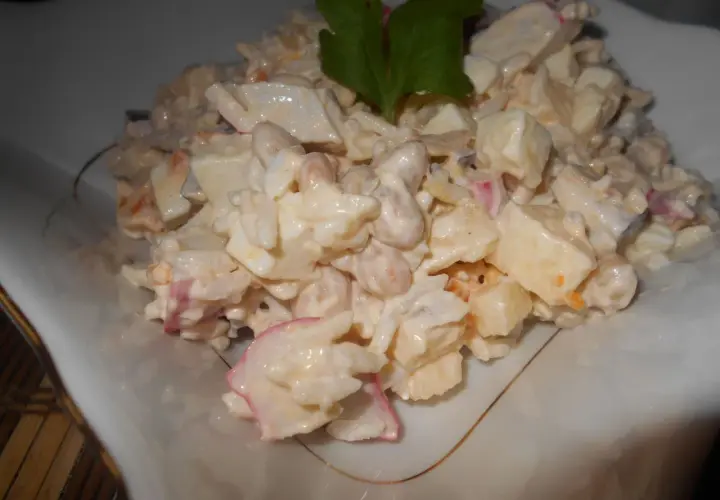 Pyszna sałatka surimi z ryżem, jajkiem i warzywami, udekorowana natką pietruszki.