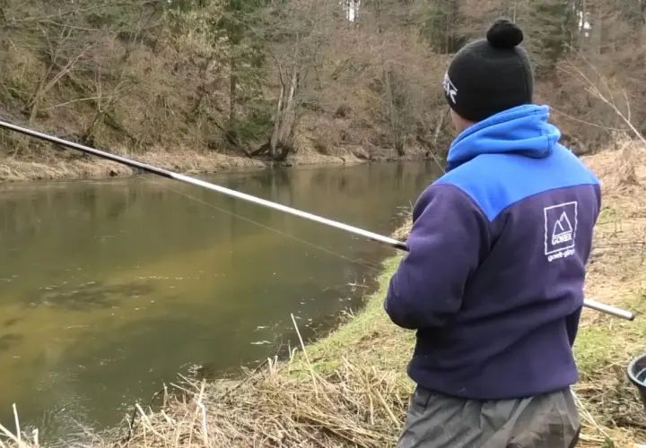 Chłopak łowi ryby na spławik nad rzeką. Pokazuje, jak łowić duże ryby na spławik.