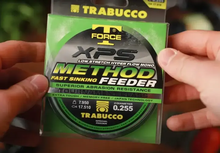 Ręce trzymają opakowanie żyłki Trabucco XPS Method Feeder. Idealna żyłka na grunt, która szybko tonie i jest odporna na przetarcia.