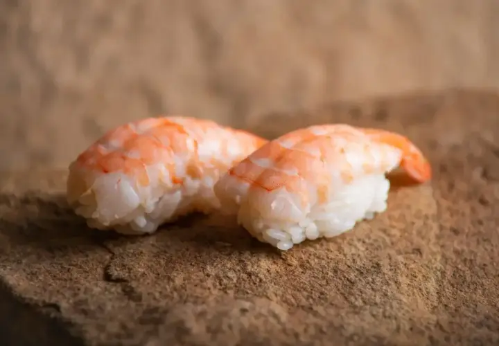 Dwa nigiri z krewetkami na kamiennym tle. Idealne, gdy zastanawiasz się, jak przygotować krewetki do sushi.