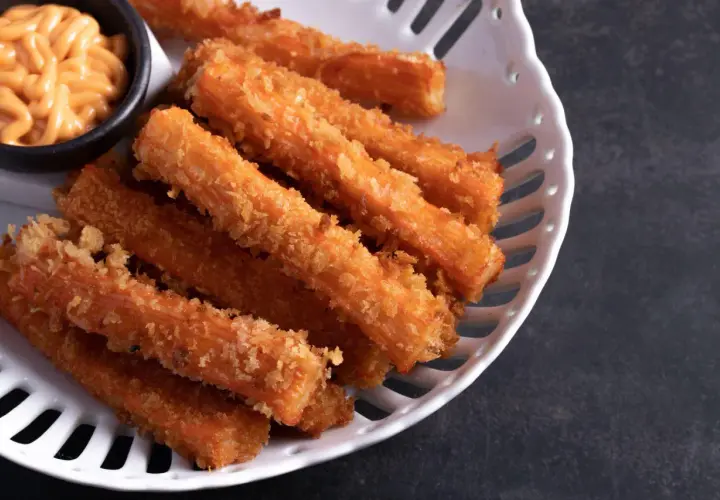 Chrupiące paluszki surimi w panierce, idealne do ciepłych dań. Podane z kremowym sosem.