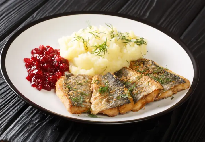 Pyszna ryba na obiad, podana z puree ziemniaczanym i żurawiną.