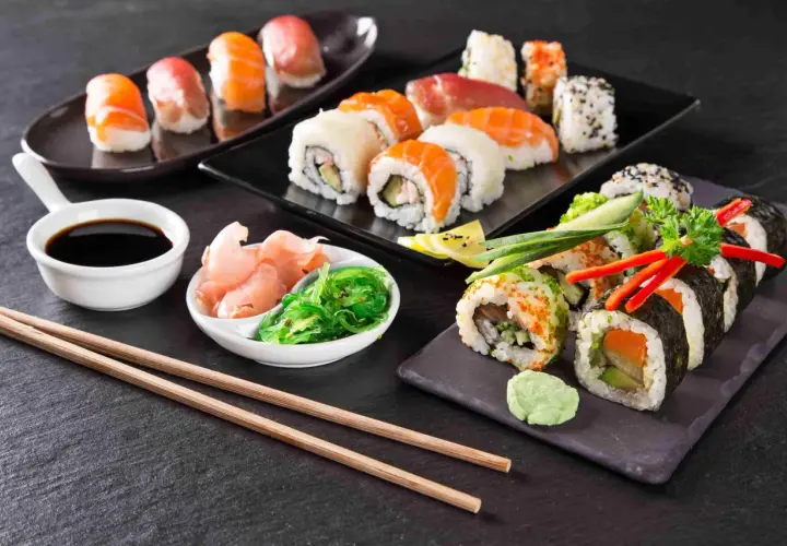 Piękne składniki sushi: nigiri z łososiem i tuńczykiem, rolki z awokado i ogórkiem, sos sojowy, imbir i sałatka wakame.