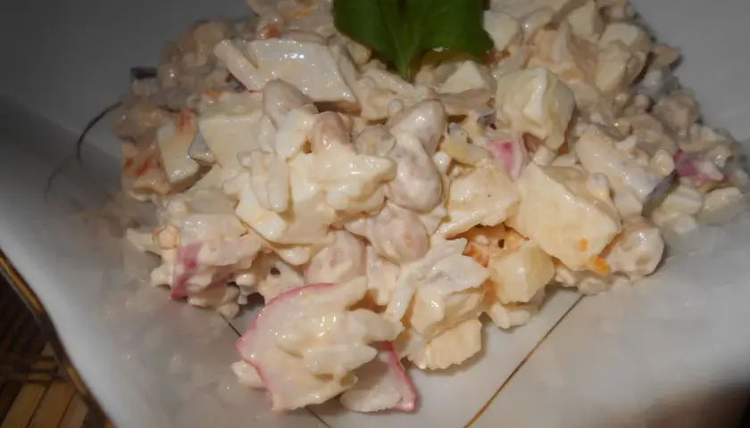 Pyszna sałatka surimi z ryżem, jajkiem i warzywami, udekorowana natką pietruszki.