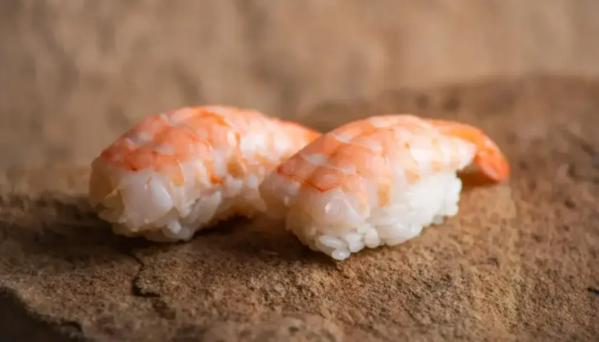Dwa nigiri z krewetkami na kamiennym tle. Idealne, gdy zastanawiasz się, jak przygotować krewetki do sushi.