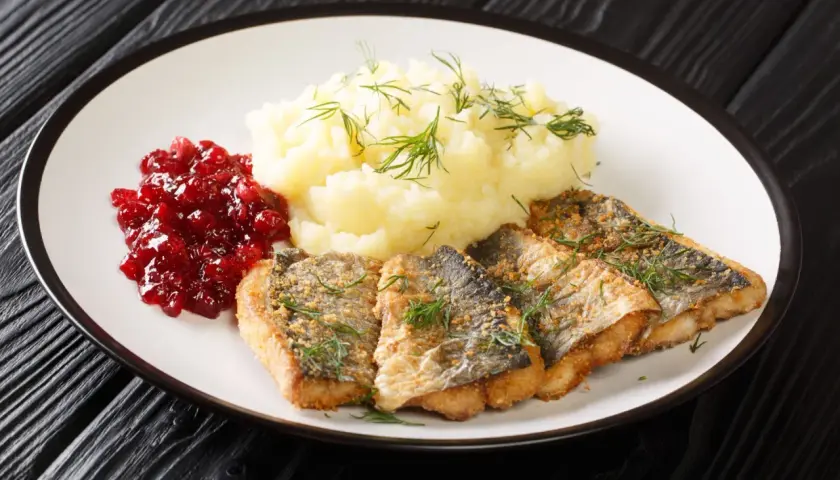 Pyszna ryba na obiad, podana z puree ziemniaczanym i żurawiną.