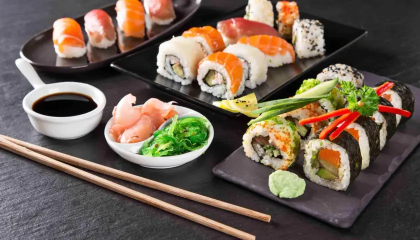 Piękne składniki sushi: nigiri z łososiem i tuńczykiem, rolki z awokado i ogórkiem, sos sojowy, imbir i sałatka wakame.