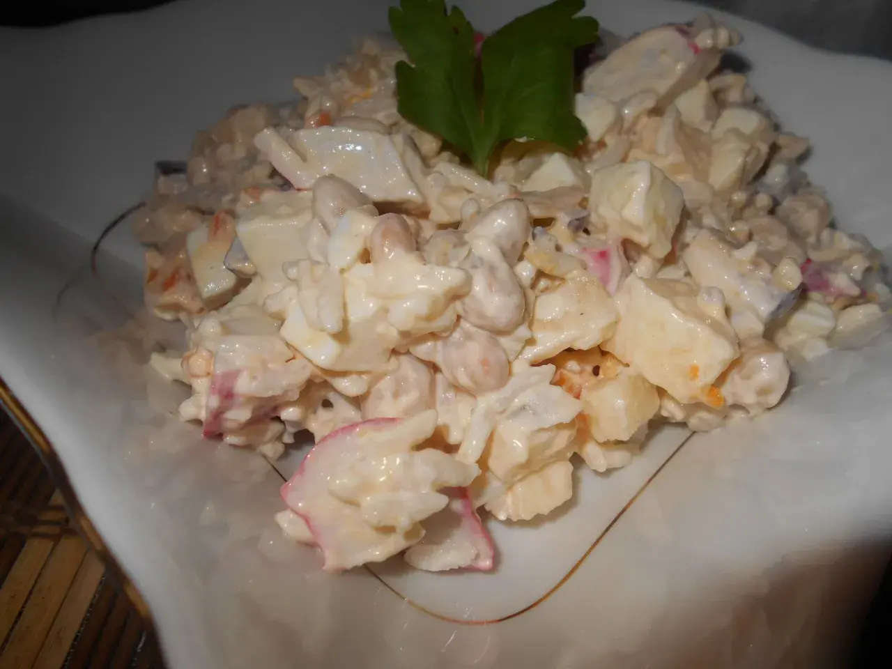 Pyszna sałatka surimi z ryżem, jajkiem i warzywami, udekorowana natką pietruszki.
