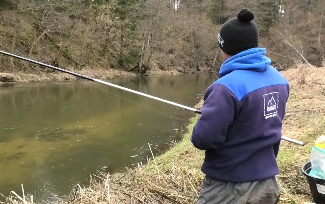 Chłopak łowi ryby na spławik nad rzeką. Pokazuje, jak łowić duże ryby na spławik.