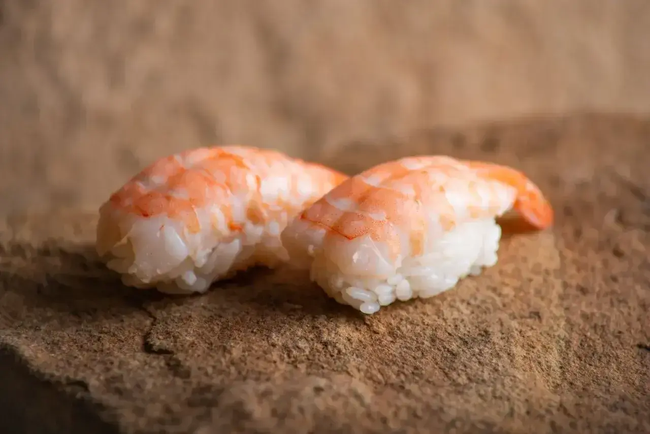 Dwa nigiri z krewetkami na kamiennym tle. Idealne, gdy zastanawiasz się, jak przygotować krewetki do sushi.