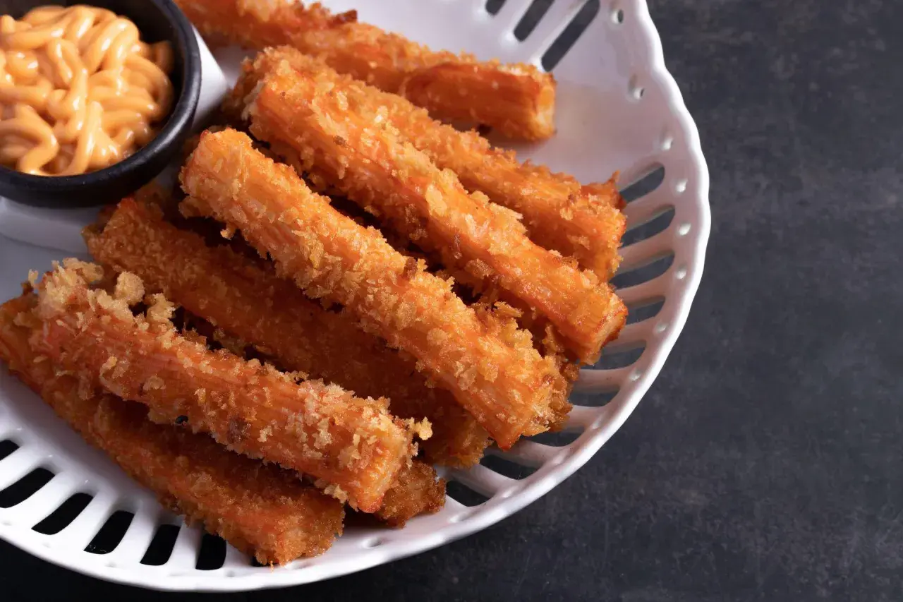 Chrupiące paluszki surimi w panierce, idealne do ciepłych dań. Podane z kremowym sosem.