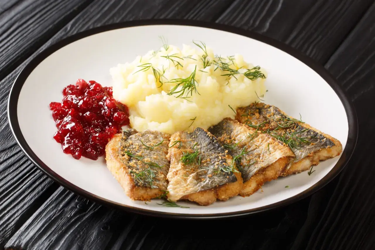 Pyszna ryba na obiad, podana z puree ziemniaczanym i żurawiną.