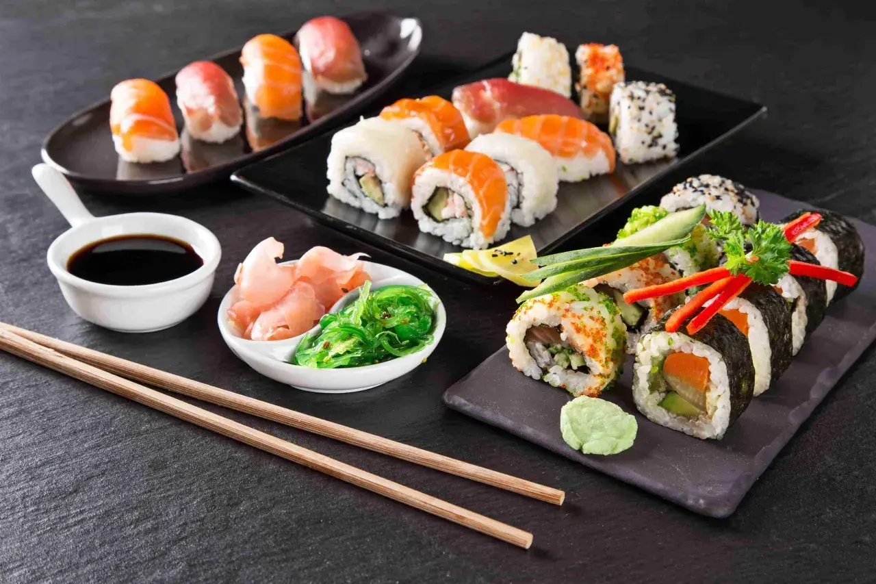 Piękne składniki sushi: nigiri z łososiem i tuńczykiem, rolki z awokado i ogórkiem, sos sojowy, imbir i sałatka wakame.