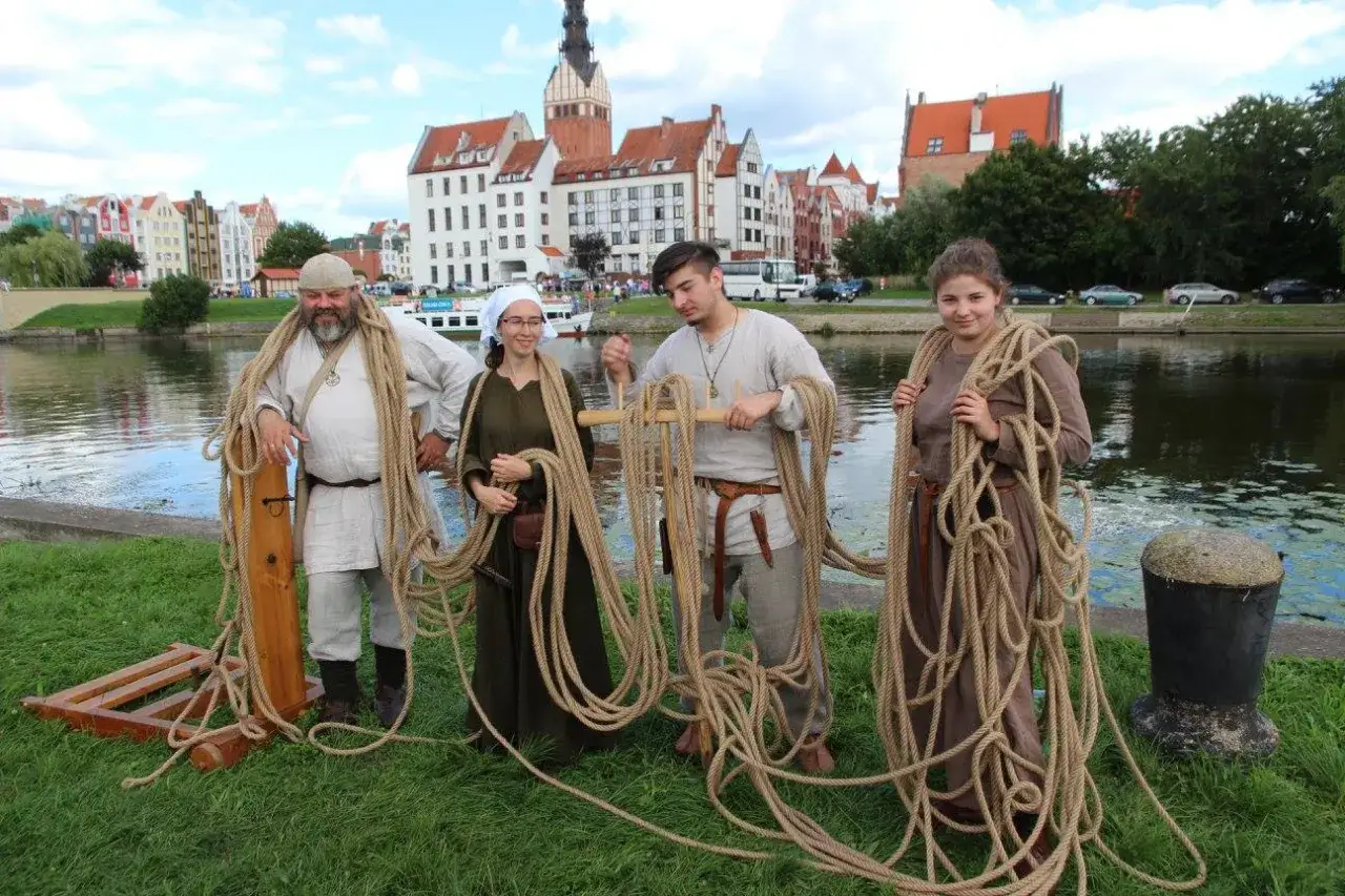 Cztery osoby w strojach historycznych trzymają grube liny, być może przygotowując się do ustanowienia rekordu lina w Polsce.